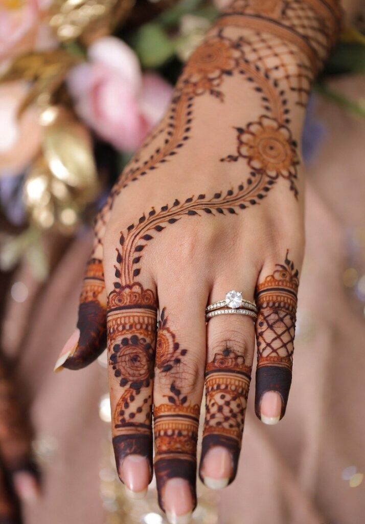Engagement mehndi design with elegant floral and geometric henna patterns on both hands featuring a beautiful diamond engagement ring.