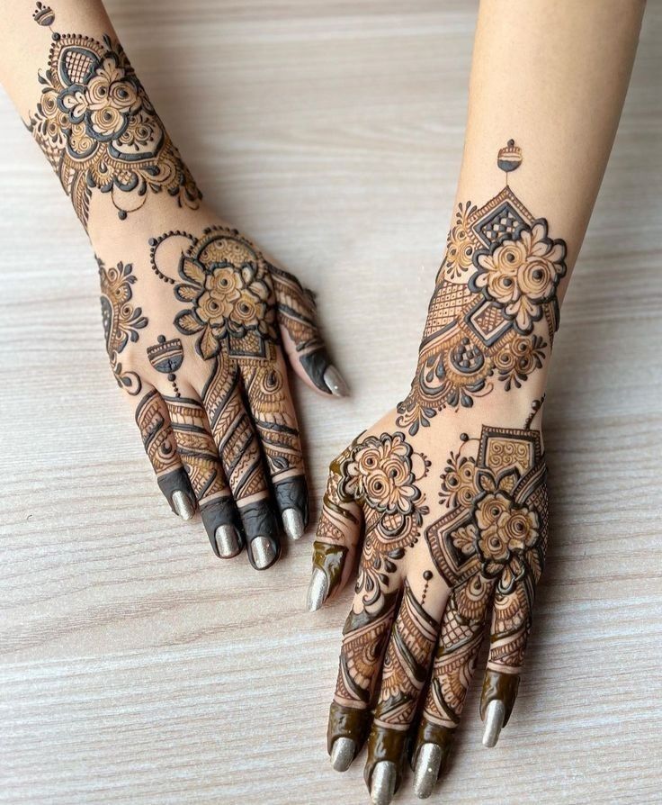 Professional mehndi artist applying engagement mehndi design on bride's palm.